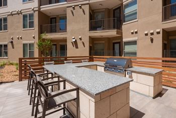 a patio with a grill and a table with chairs